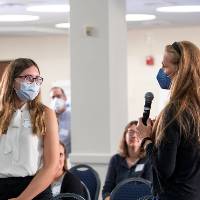 Mentor introducing scholar, both wearing masks.